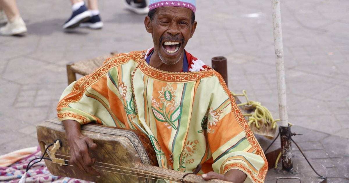 A Gnawa maâlem singing and playing the guembri in the square